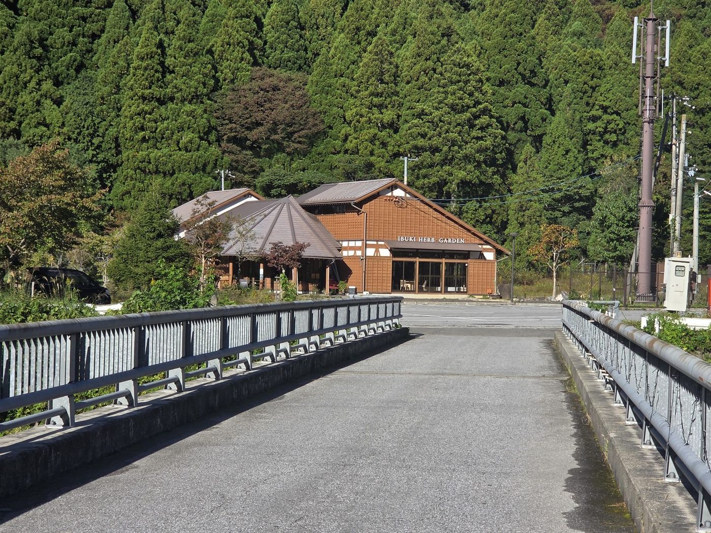 橋を渡った先に、茶色い木造のいぶきハーブ・ガーデンの建物が見える